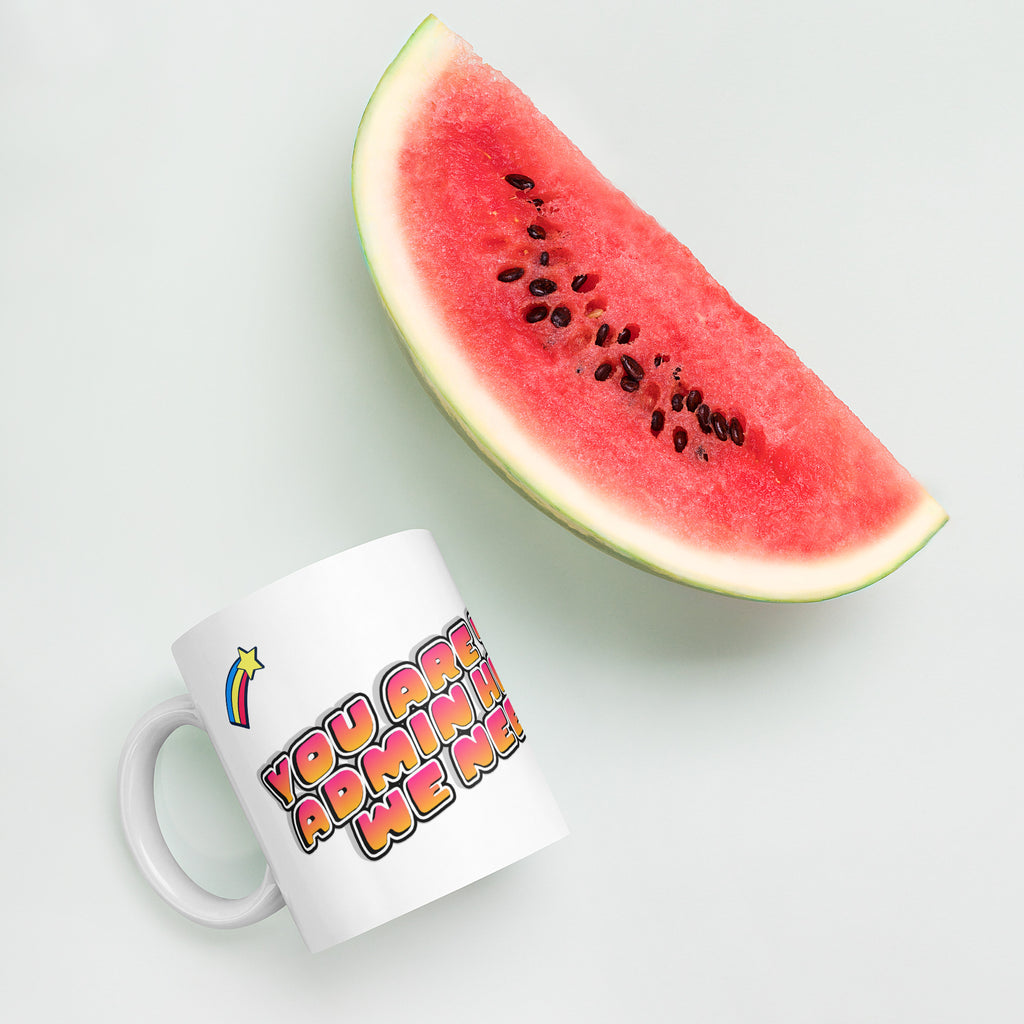 White mug with colorful text next to a slice of watermelon on a light background