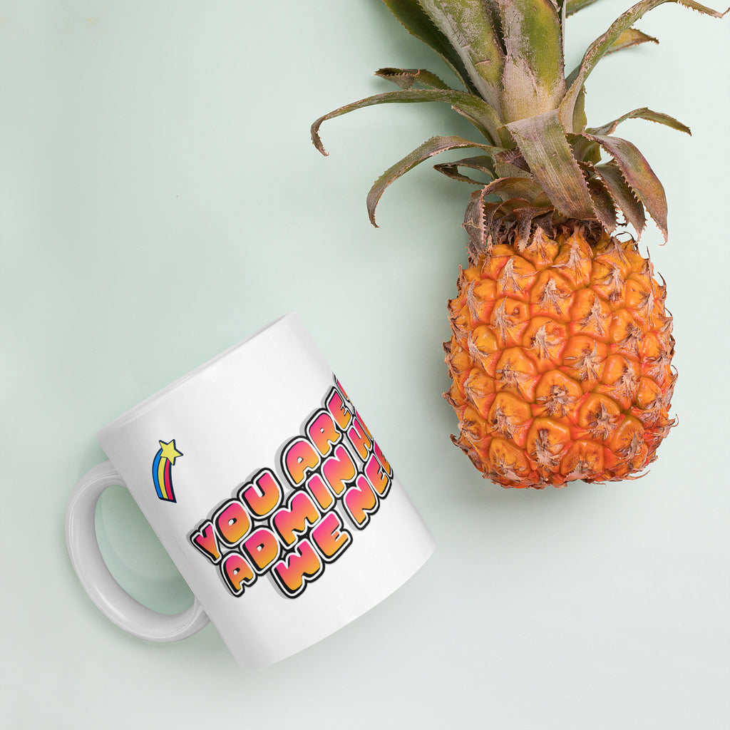 White mug with colorful text next to a pineapple on a light green background