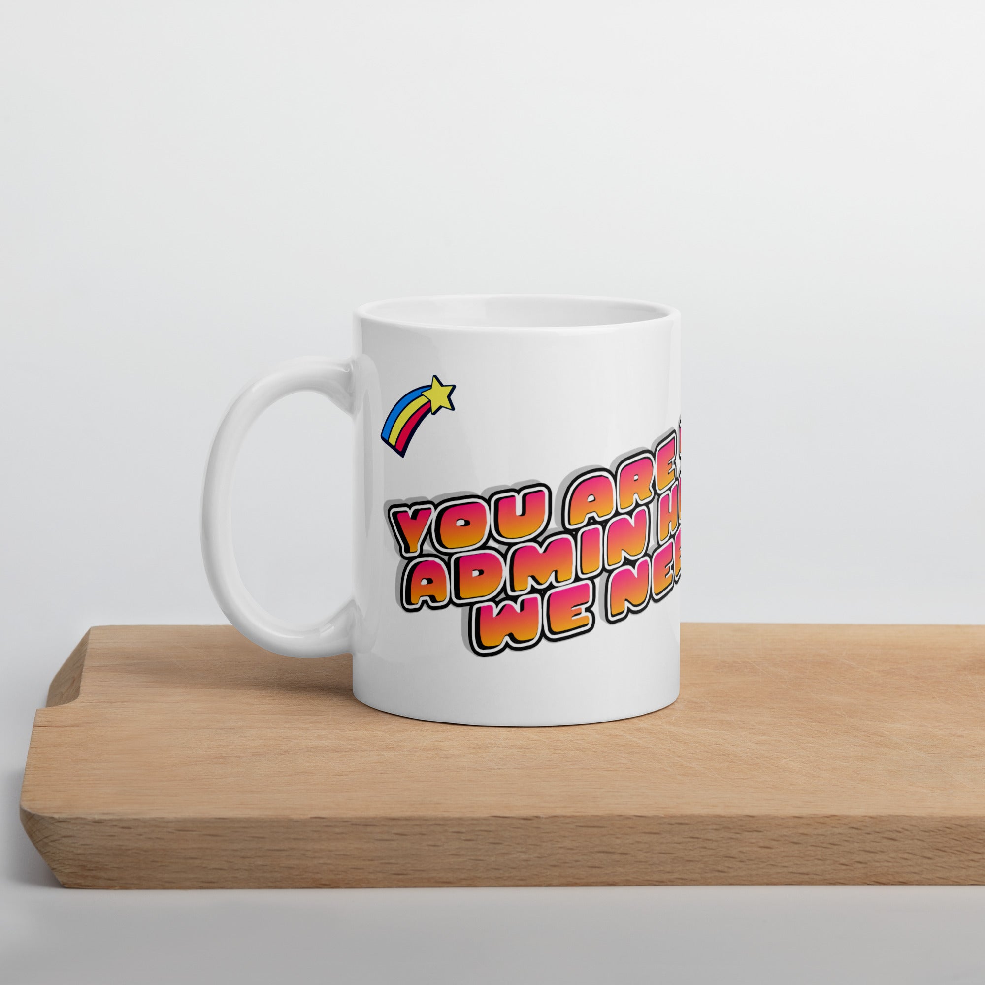White mug with colorful text and rainbow design on a wooden surface