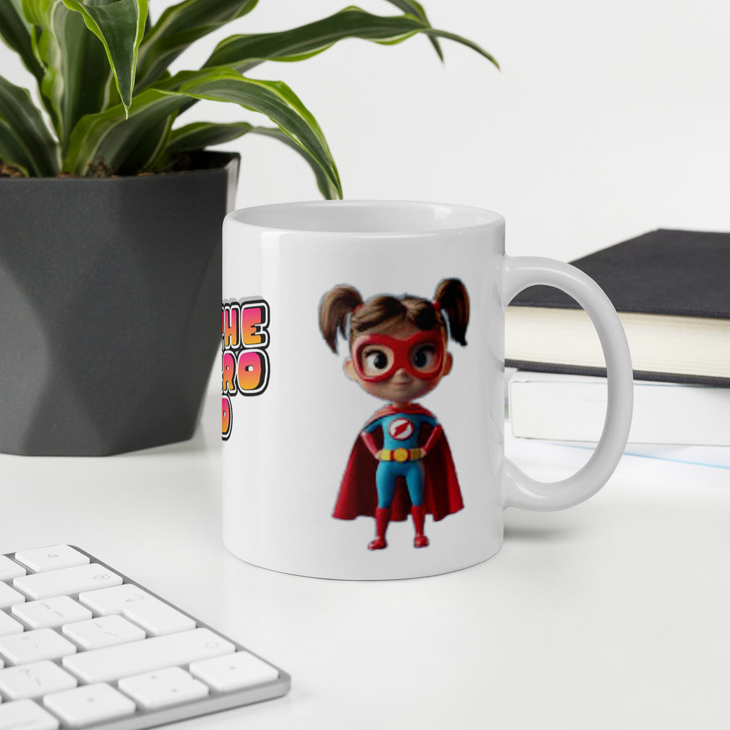 Mug with superhero design on a desk with keyboard, plant, and books.