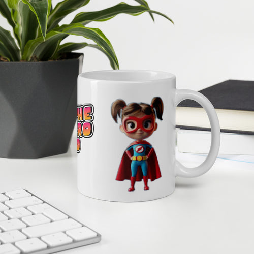 Mug with superhero design on a desk with keyboard, plant, and books.