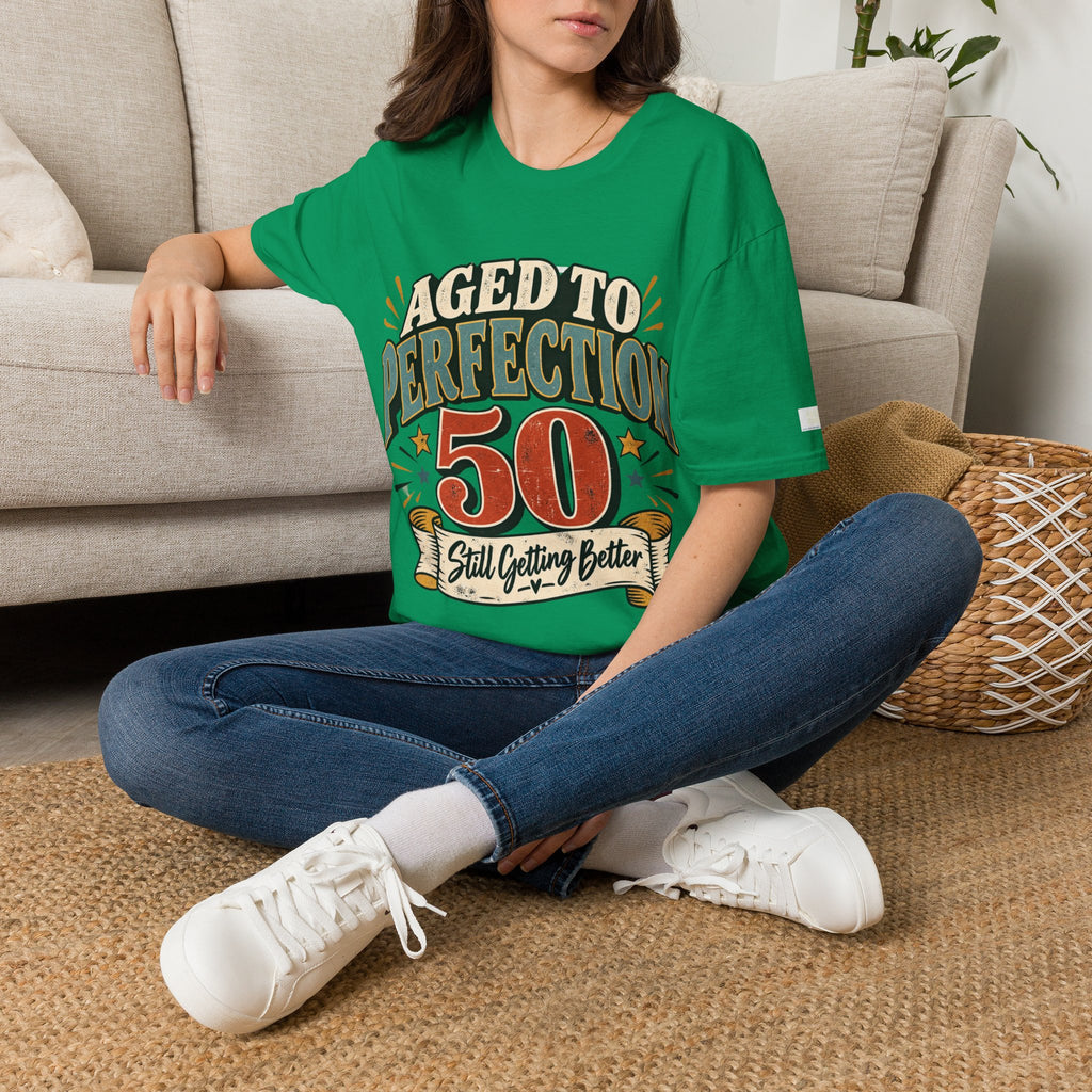 Person wearing a green t-shirt with a birthday message, sitting on a carpeted floor.