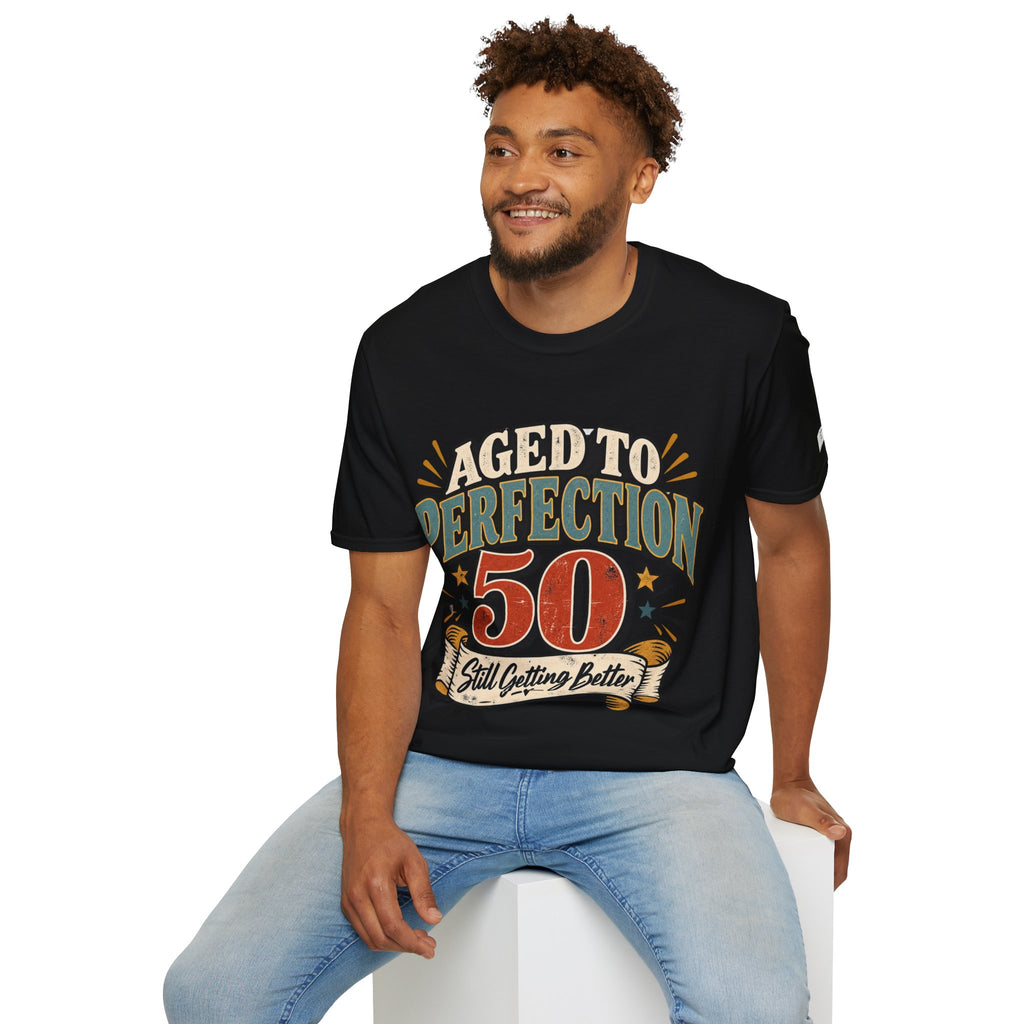 Man wearing a black t-shirt with a graphic design of plants and text, sitting on a white stool against a white background.