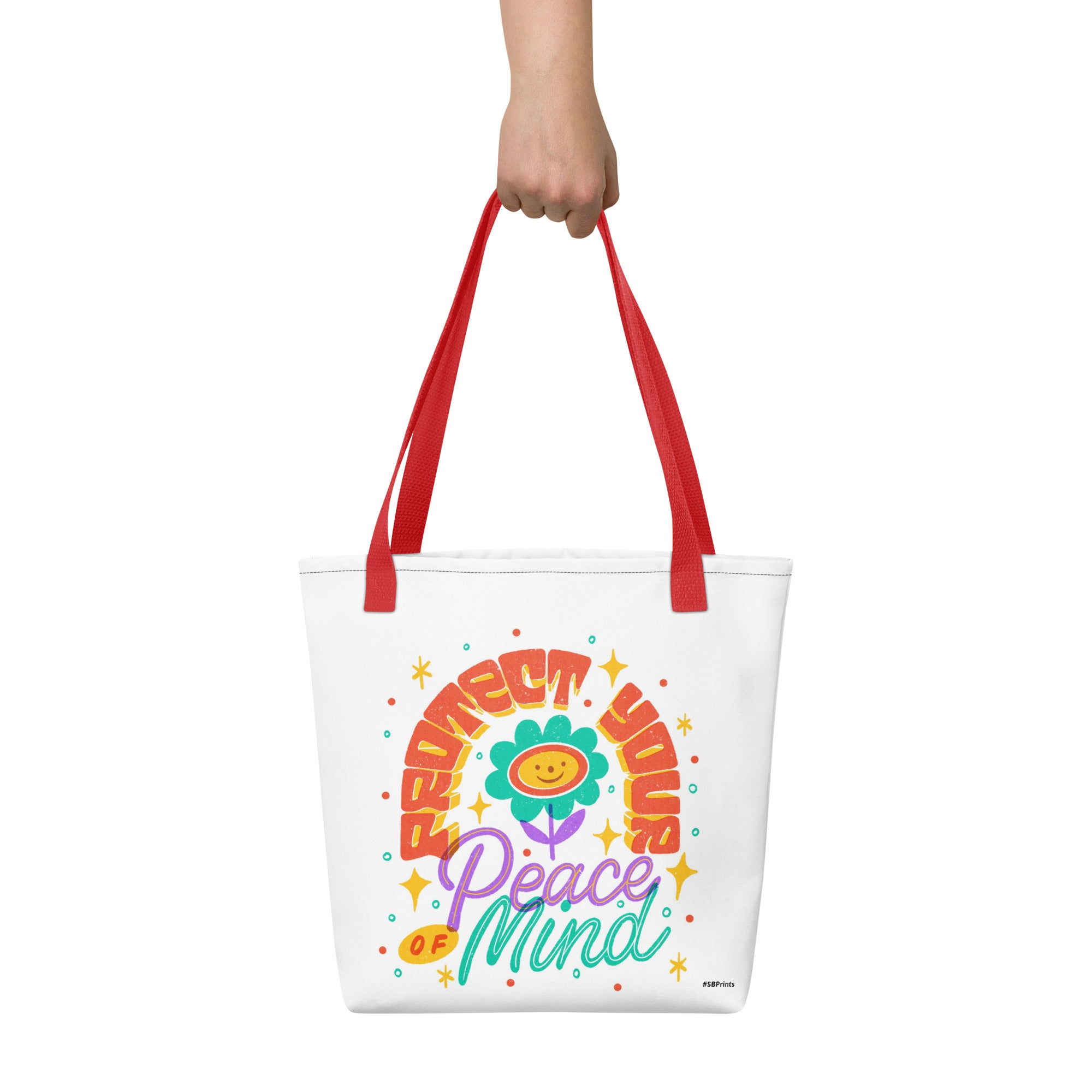 Tote bag with colorful design and text held by a hand on a white background