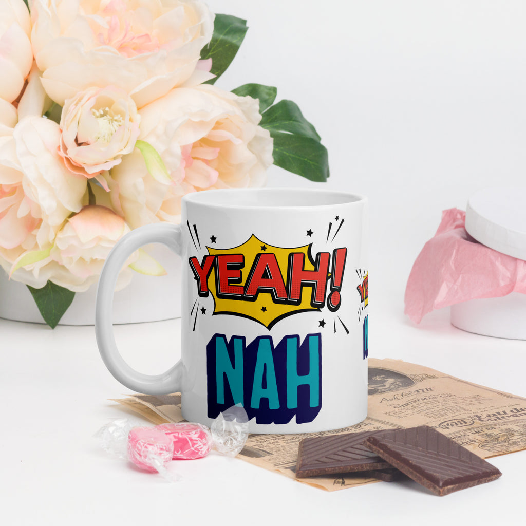 White mug with 'Yeah! Nah!' design on a table with flowers and snacks