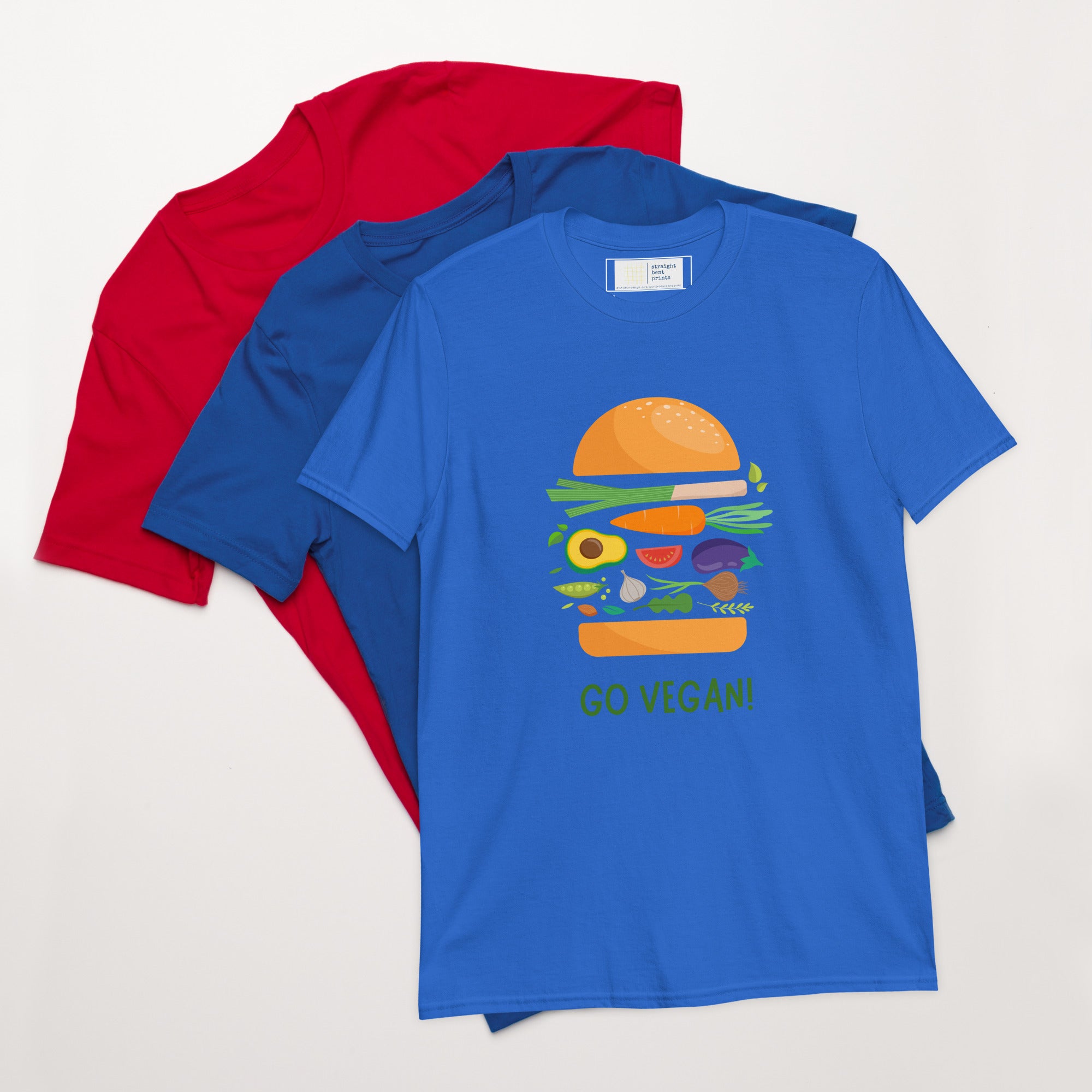 Blue t-shirt with a colorful burger graphic and 'Go Vegan!' text, folded with red and blue shirts on a white background.