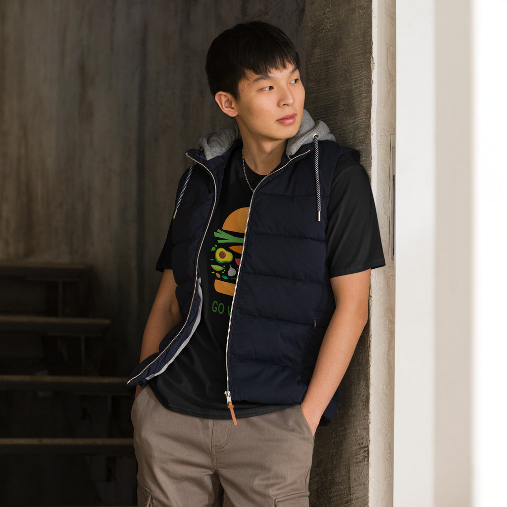 Person wearing a black puffer vest over a graphic t-shirt, standing against a neutral wall.