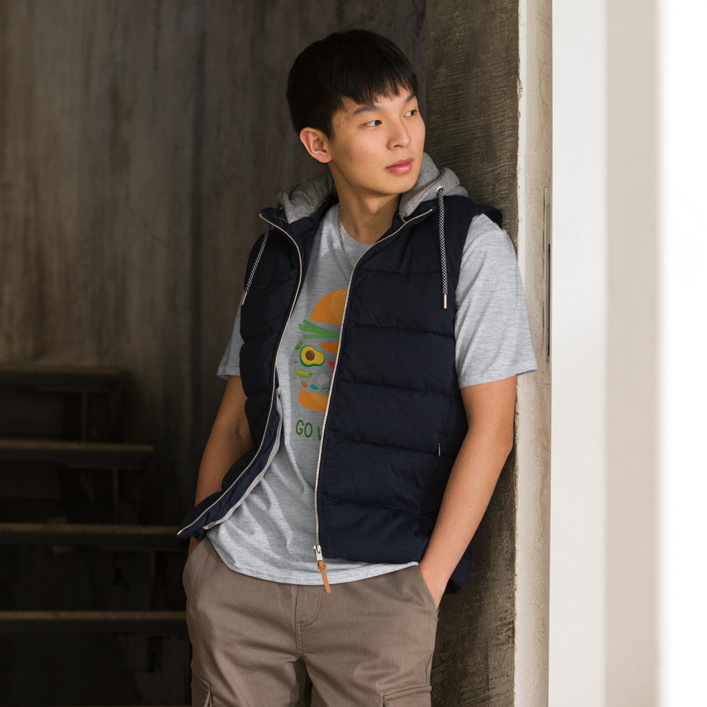 Person wearing a black puffer vest over a gray shirt with a graphic design, standing against a neutral wall.
