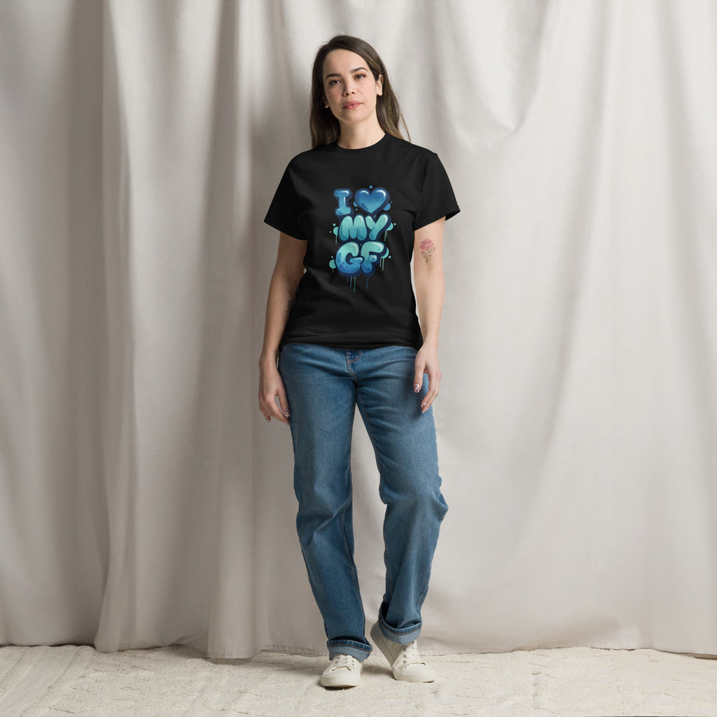 Person wearing a black t-shirt with colorful text design and blue jeans against a plain background