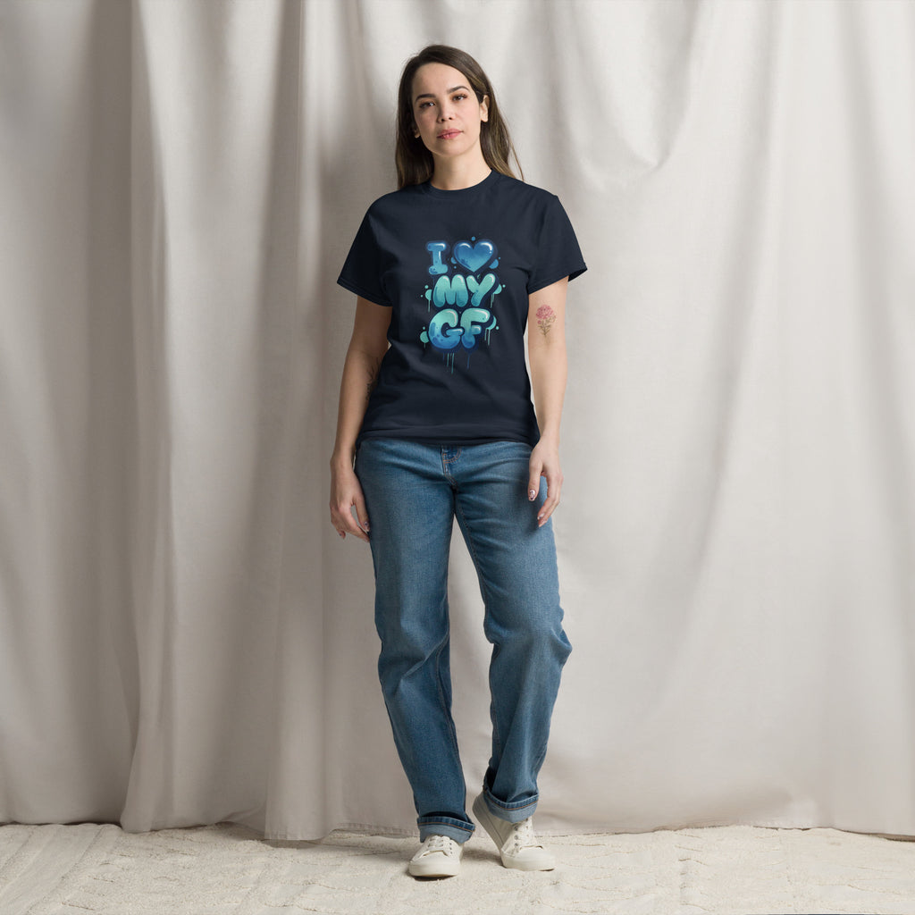 Person wearing a black t-shirt with colorful text design and blue jeans against a plain background