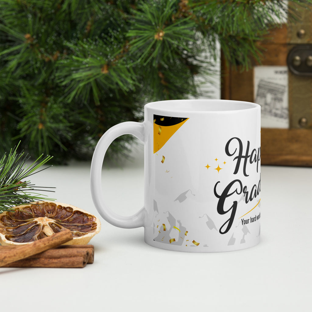 White mug with 'Happy Grad' text on a table with Christmas decorations