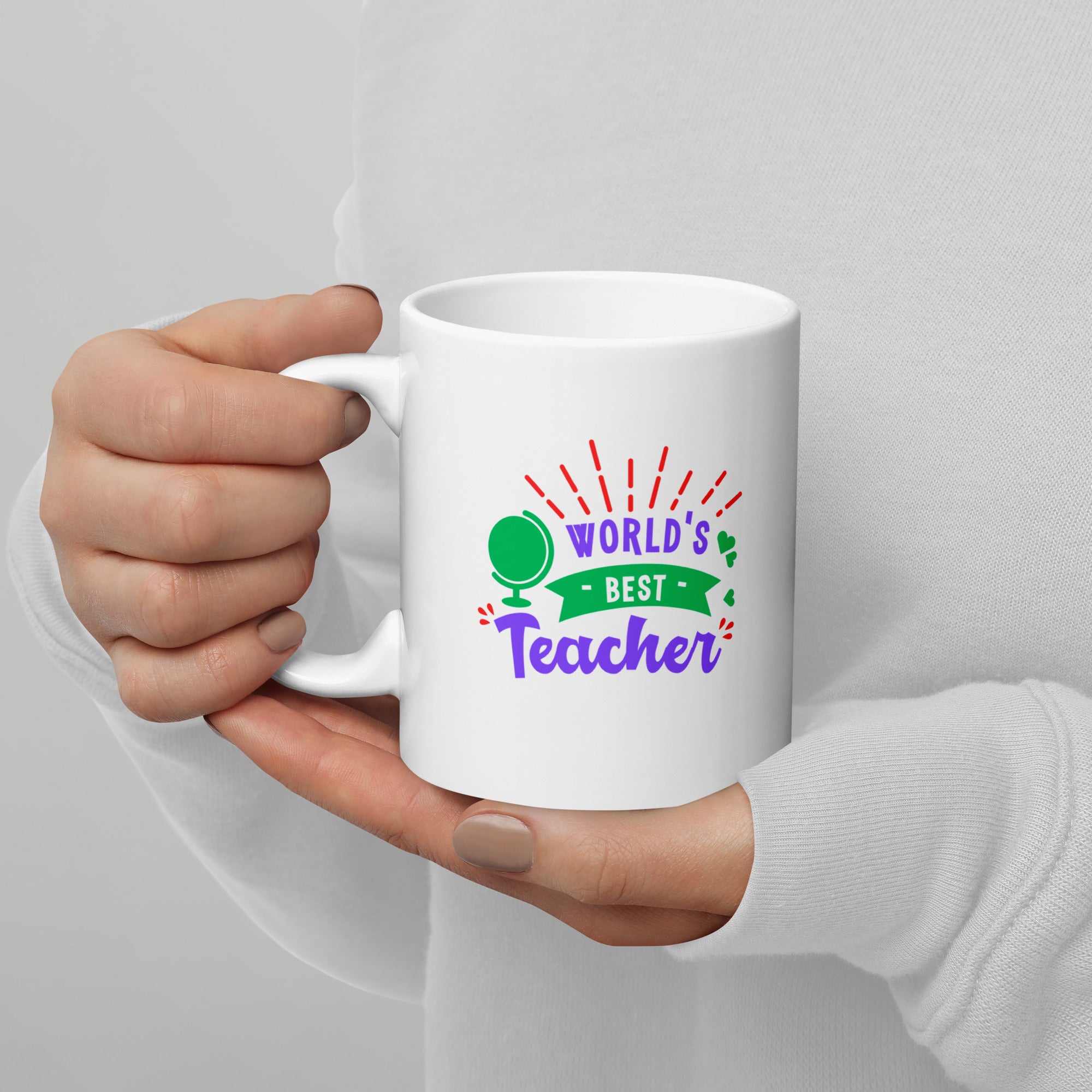 White mug with 'World's Best Teacher' text held by a person against a gray background